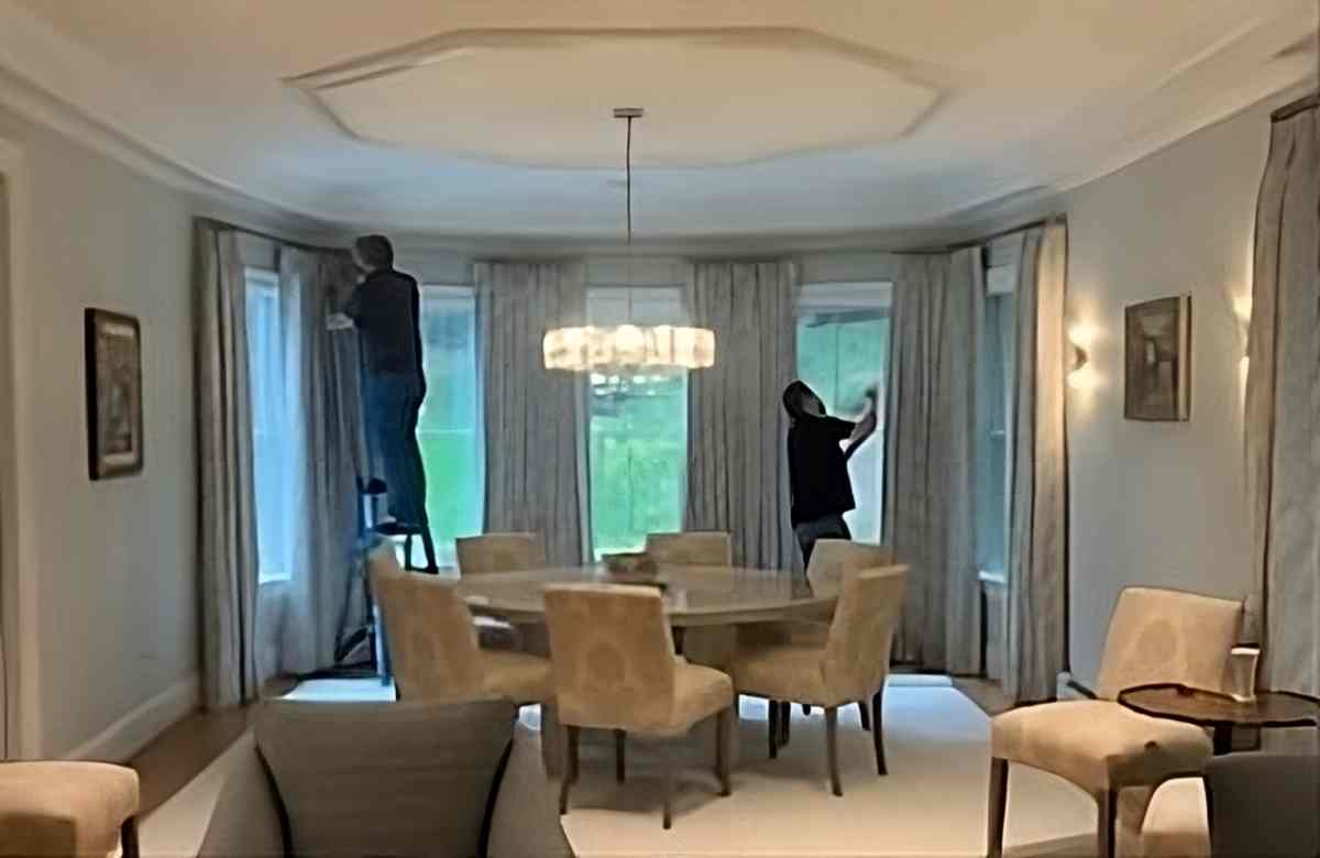  A professional using his skills to hang dark curtains at their average length in a home near Southborough, MA